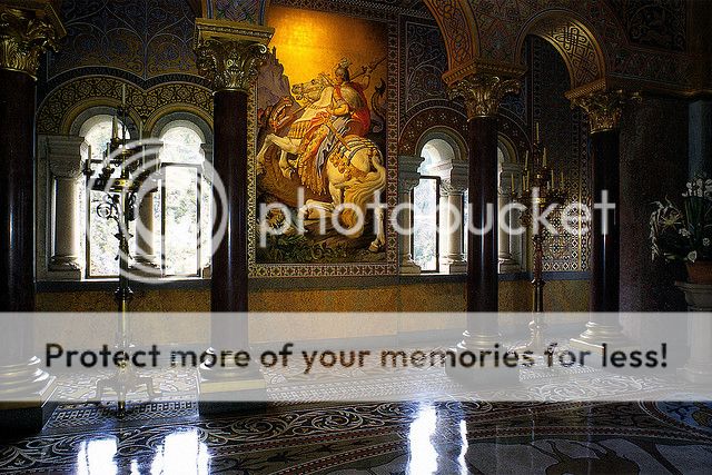 The coronation room of Neuschwanstein. The mural is of St George. The floor is an intricate mosaic tile. Most of the decoration is paint. Jewels in the chandeliers are made of glass.