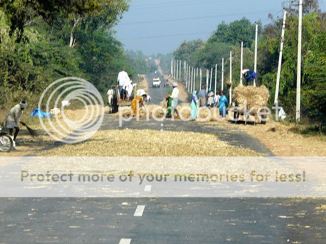 Villagers make use of passing cars to thresh grains. Highway to Hassan from mysore